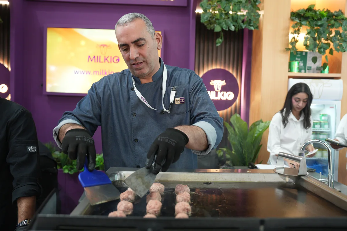 Chef in black gloves cooking meatballs on a flat grill